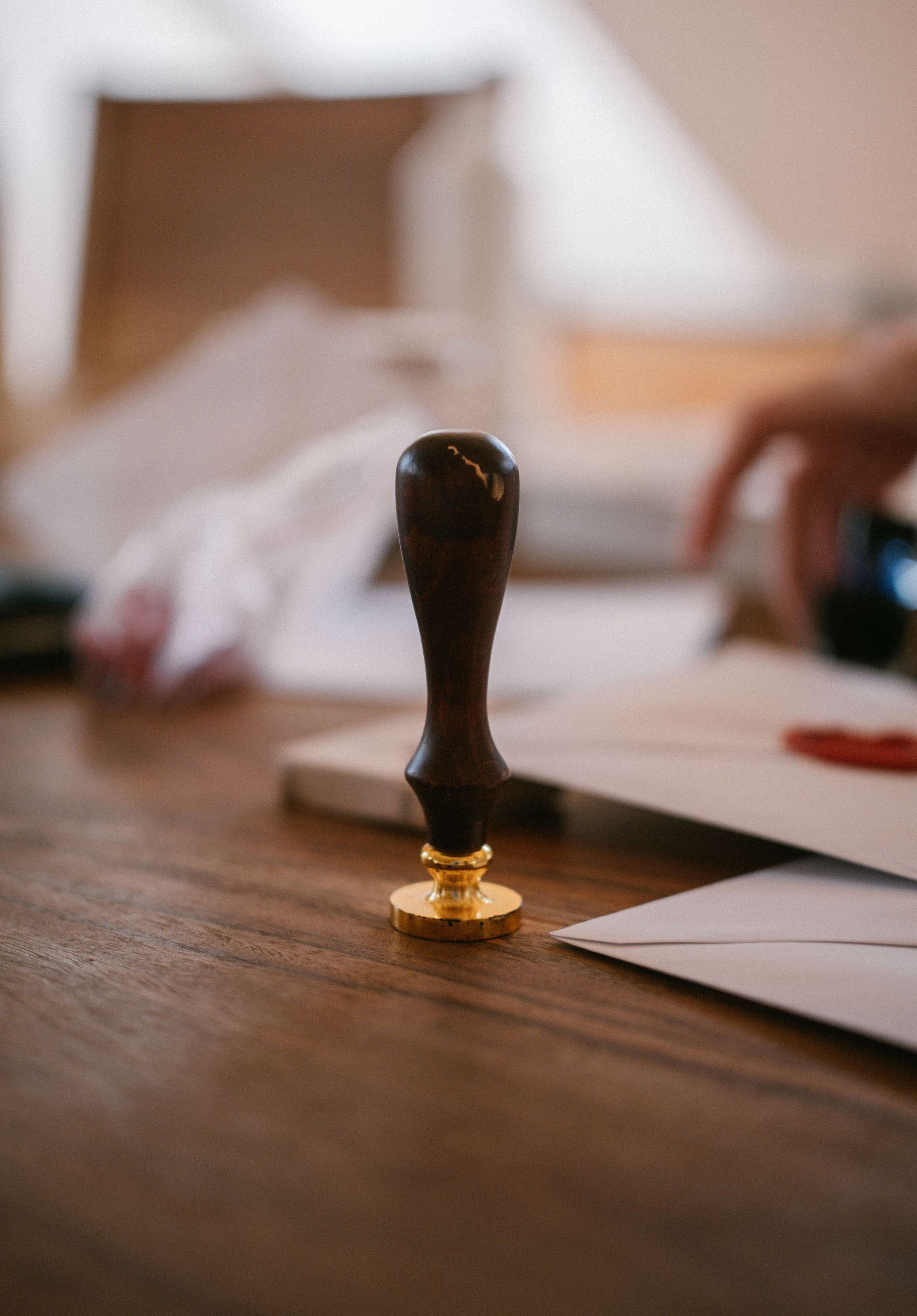 A close-up of a vintage wax seal stamp on a wooden desk with envelopes, conveying an old-world charm.